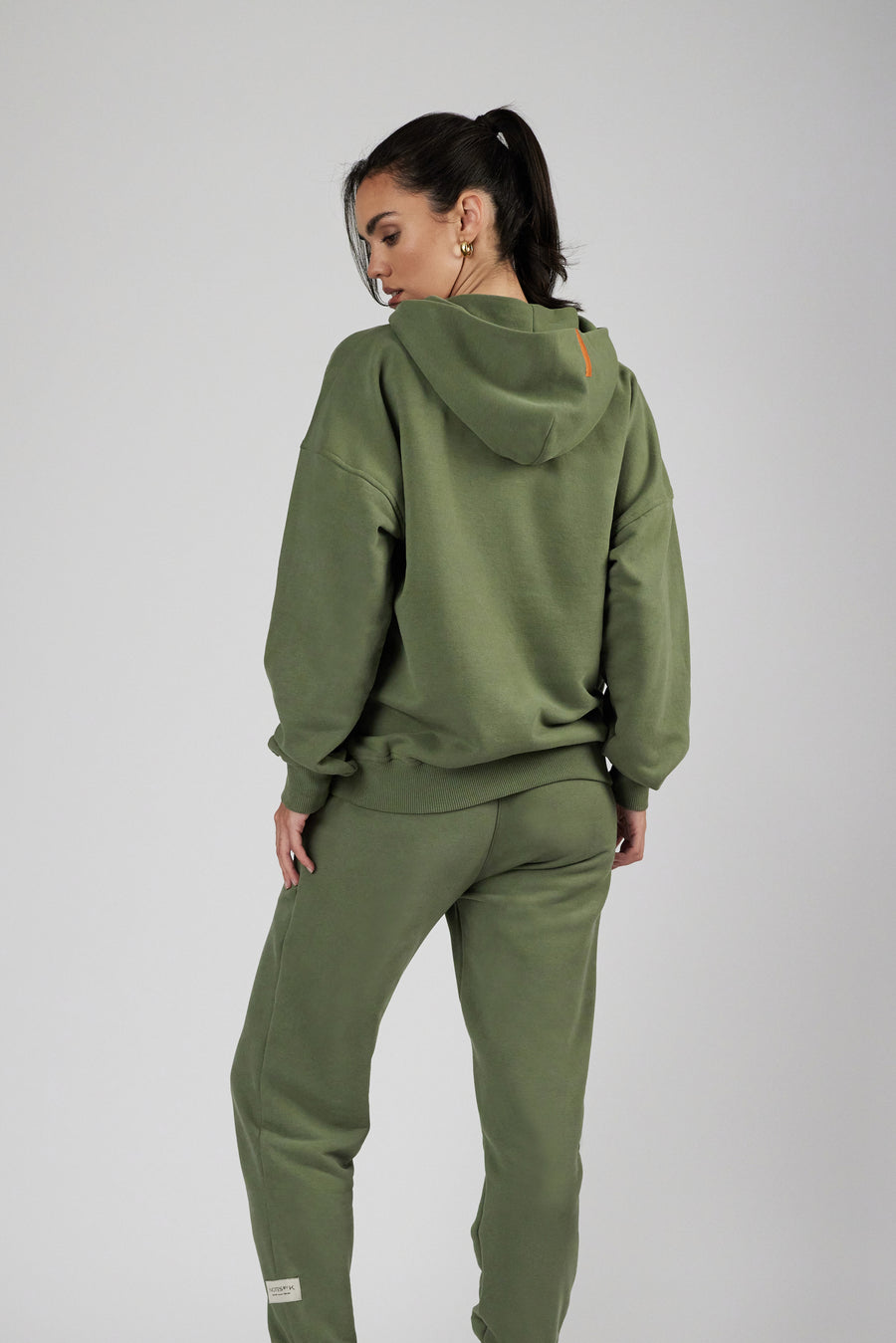 Backside of woman wearing unisex sweatpants and hoodie in color sage green