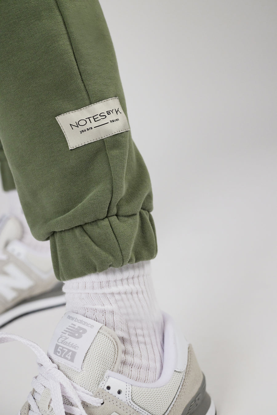 Woven label detail on bottom hem of a sweatpants in color sage green