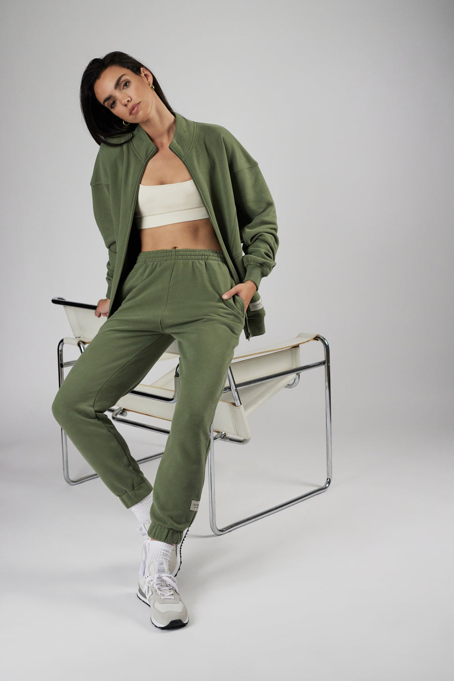 Woman wearing unisex sweatpants and zipper jacket in color sage green