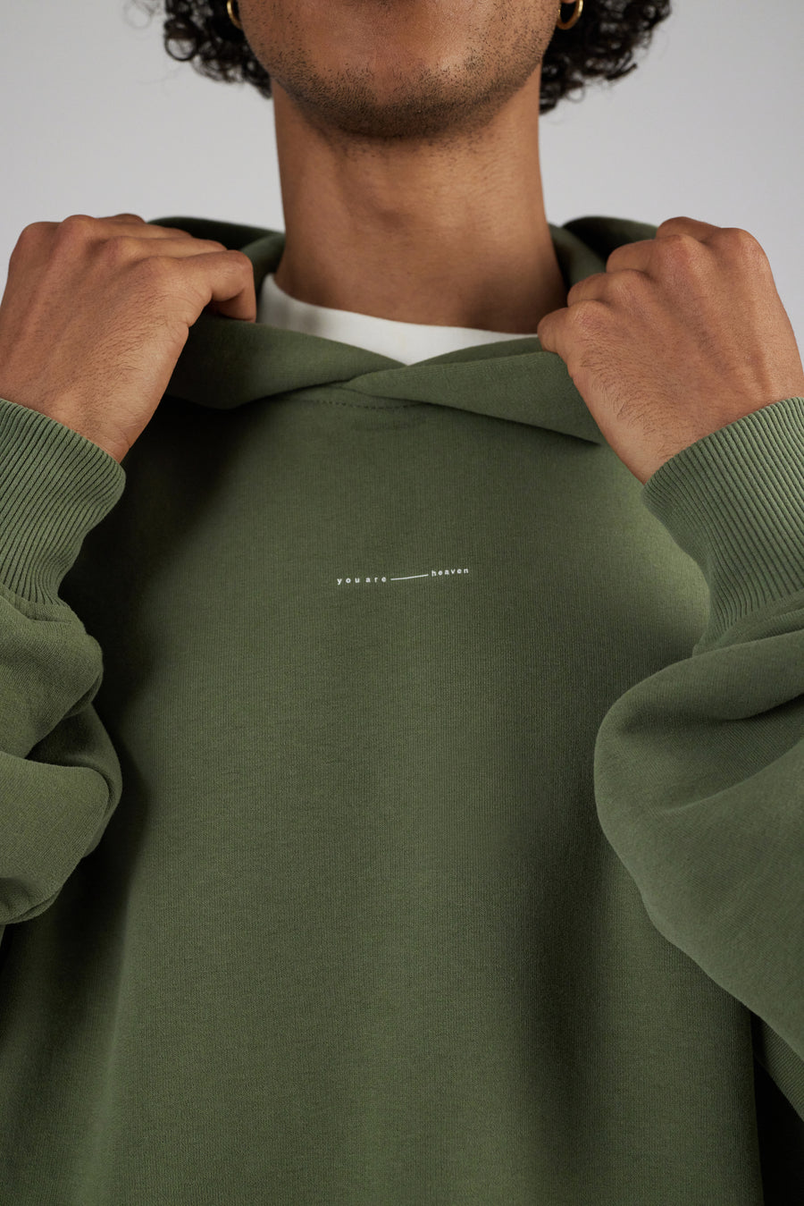 Men wearing a hoodie in color sage green with printed wording detail at front upper chest