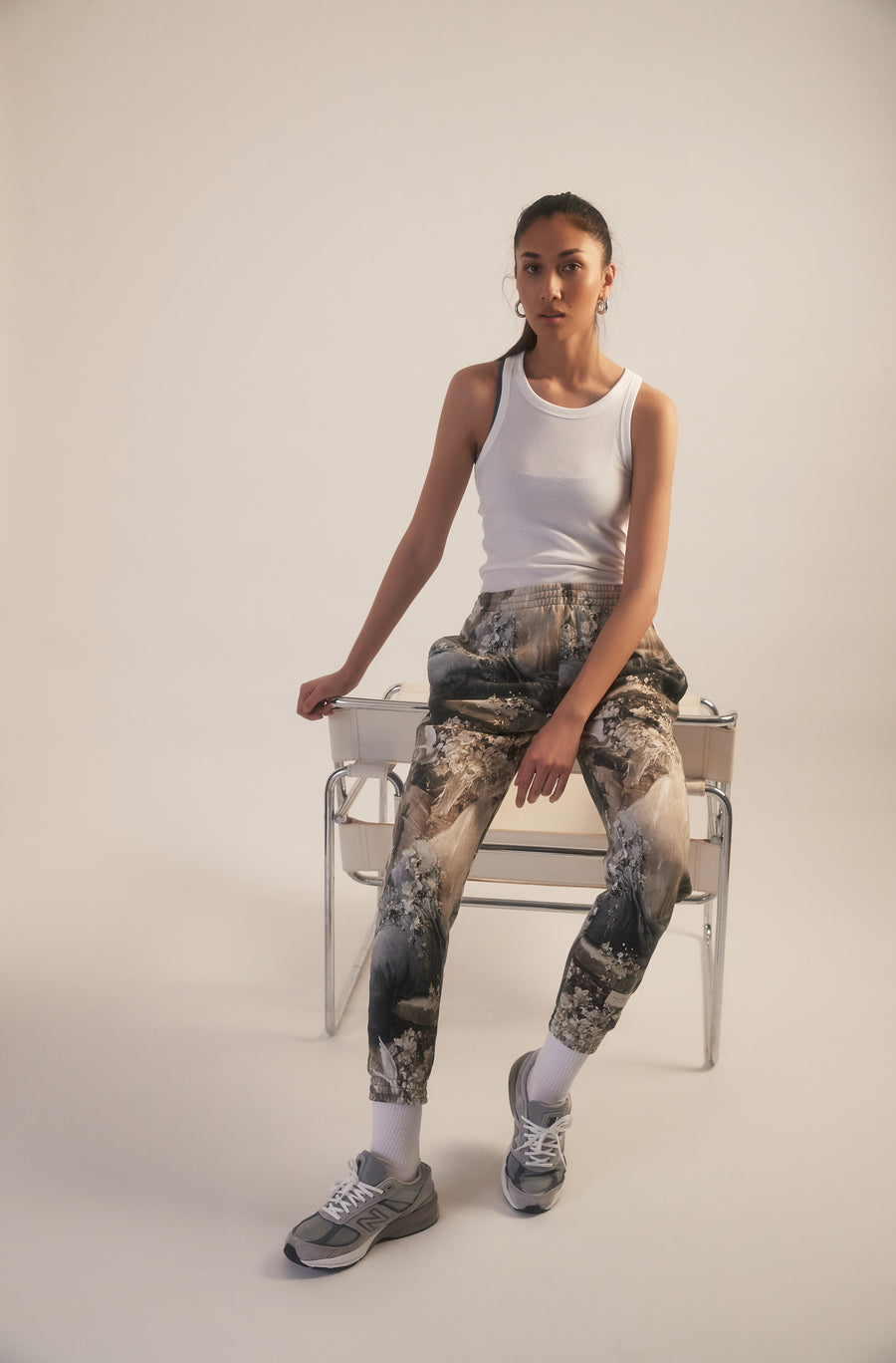 Woman leaning on a chair an wearing allover printed sweatpants and an uni white top